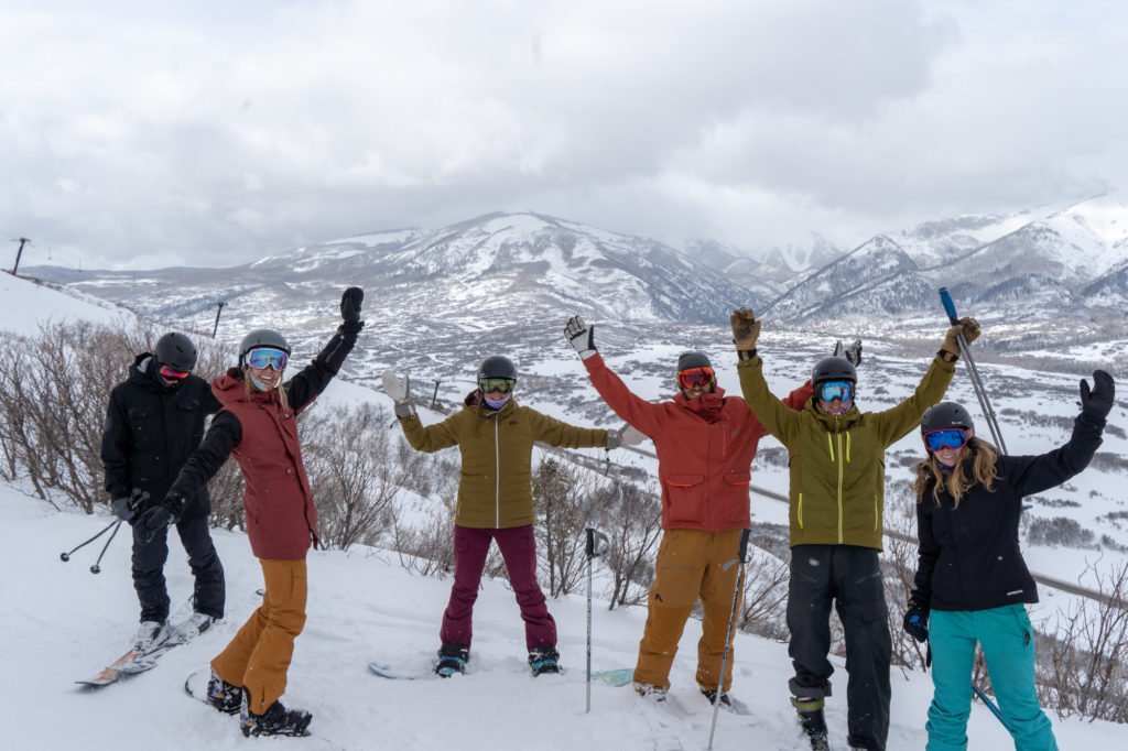 Group of young adults waving at top of mountain