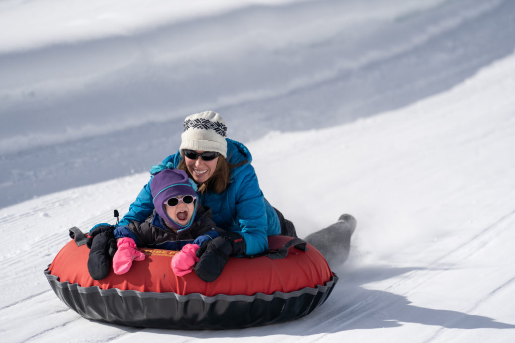 mom and daughter snow tubing together